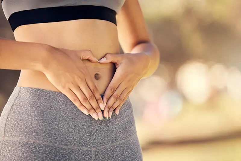 Dame som former et hjerte med hendene over magen